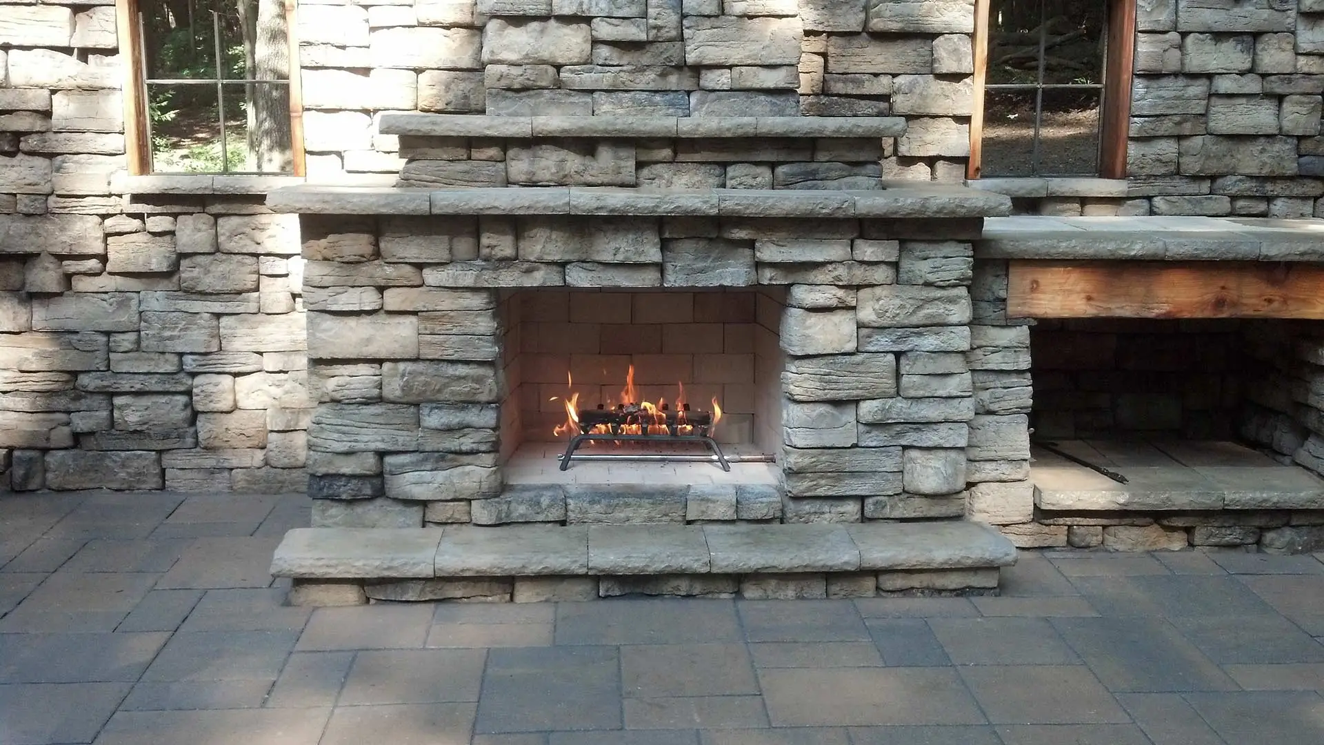 Custom stone outdoor fireplace on a home property in Spring Lake, MI.