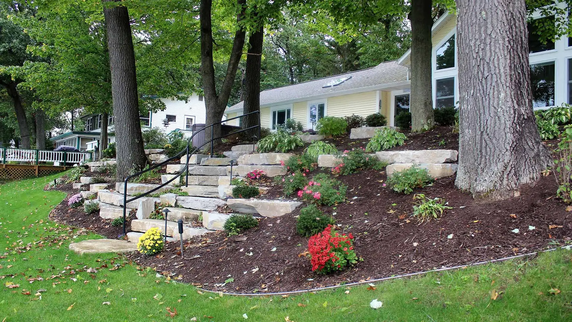 Large mulch flower bed and stone landscaping design in Ada, MI.