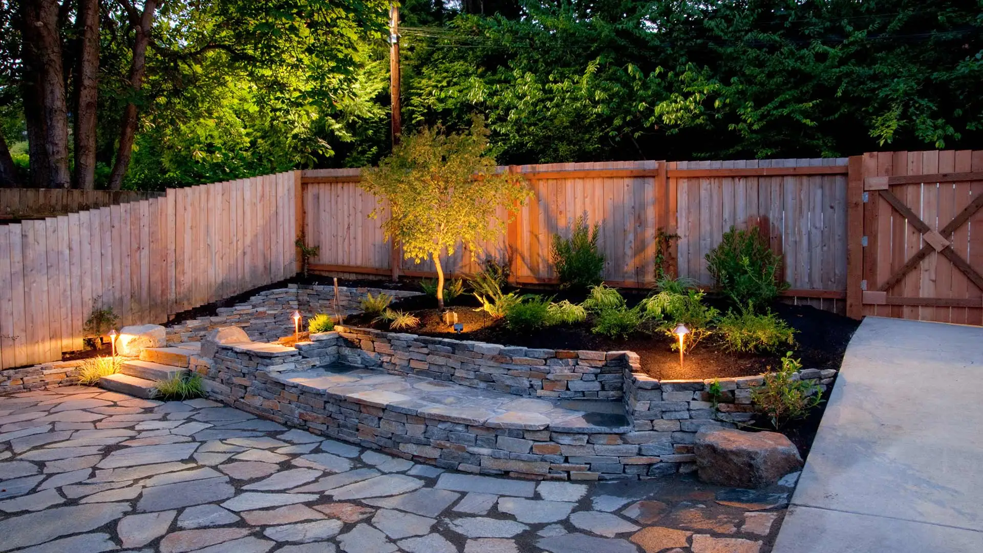 Custom stone patio with retaining wall and outdoor lighting in Cascade, MI.