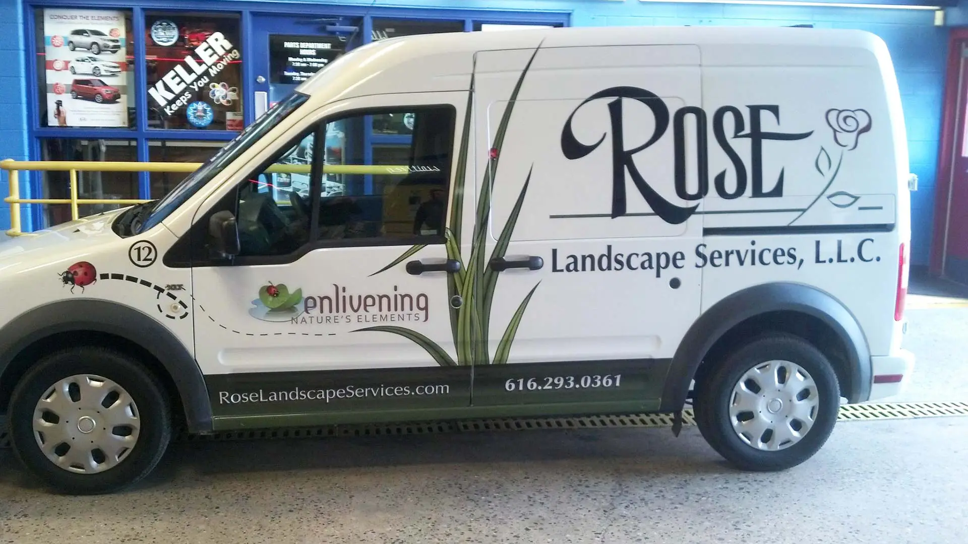 Landscaping company work van with logo and phone number.