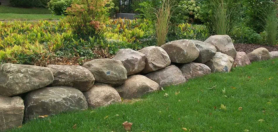 Custom boulder retaining wall and flower bed in Cascade, MI.