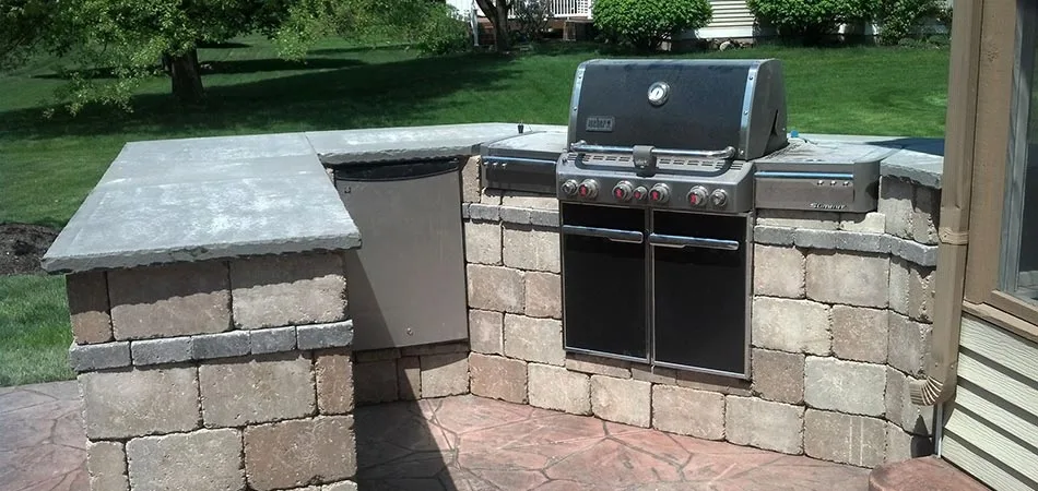Outdoor kitchen cooking area with gas grill and stone countertop in Cascade, MI.