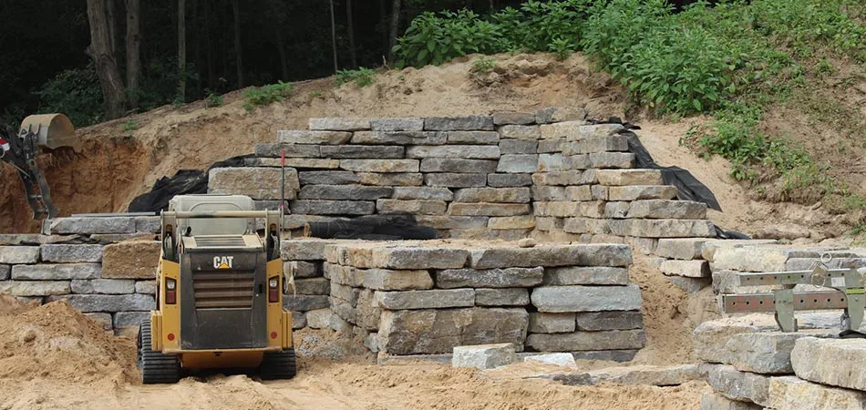 Custom stone retaining wall and outdoor living area being constructed in Cascade, MI.