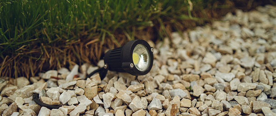 A black outdoor light pointed towards a wall in Lowell, MI.