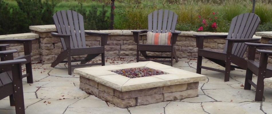 Seating wall installed around fire put with lounge chairs added in Marne, MI.