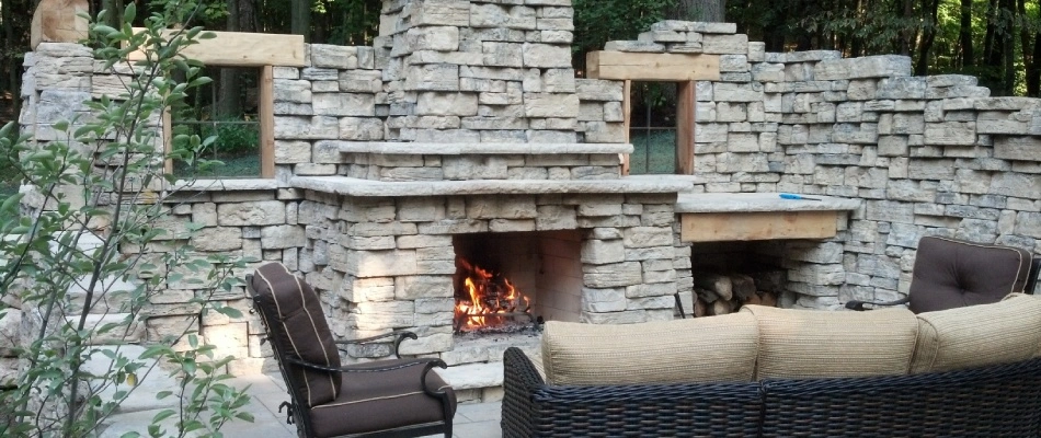 Outdoor fireplace with lounging area in front of it in Kentwood, MI.